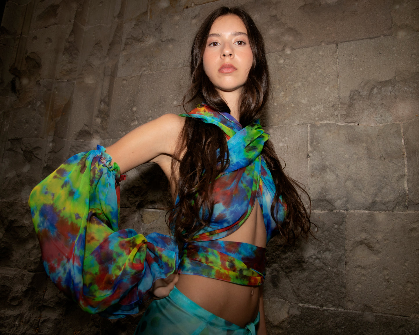 Woman wearing Angelica top in Daydream against a stone wall.