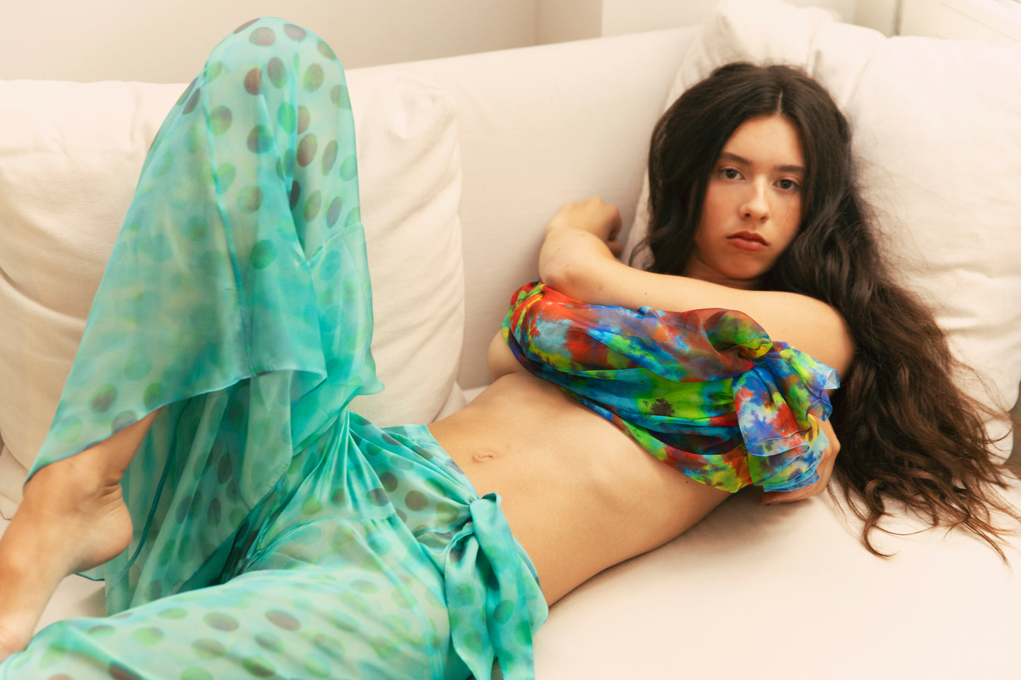 Woman in Dramatica pants in acqua salata with colorful patterns against white sofa