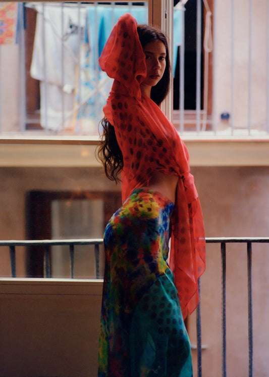 Woman wearing Electrica blouse in Cherry Sangria standing on a balcony.