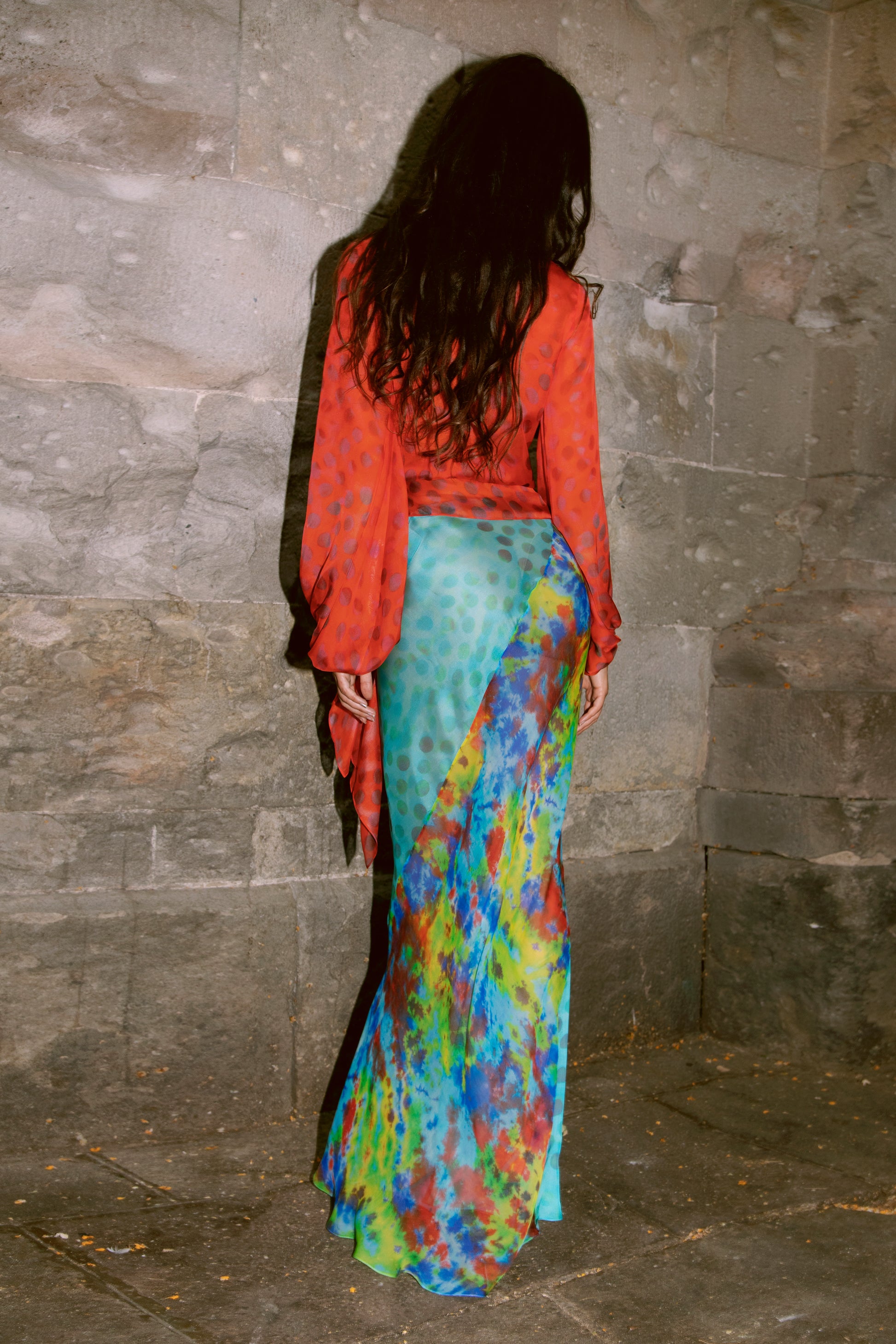 Woman wearing Exotica skirt in daydream against stone wall